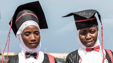 Two young women pose for a portrait, dressed in robes after collecting their Bachelor degrees in Conakry on October 12, 2020. - Presidential elections are to be held on October 18, with incumbent President bidding for a third term in office, defying critics who say he forced through a new constitution this year enabling him to sidestep two-term presidential limits.